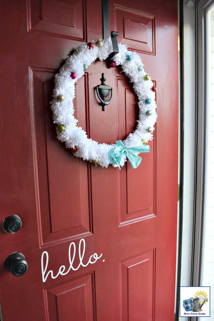 White pom pom Christmas wreath on red door