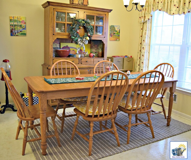 Yellow kitchen with gray and white striped wool rug and oak farmhouse table