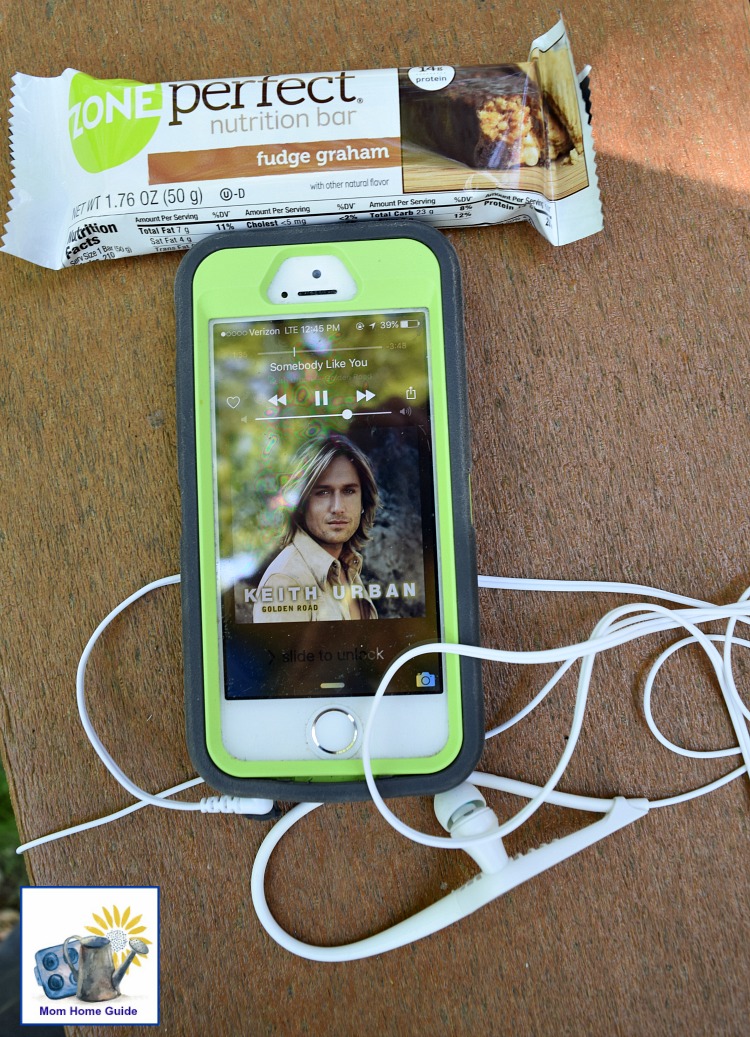 iPhone with earbuds and ZonePerfect bar for a nature trail walk