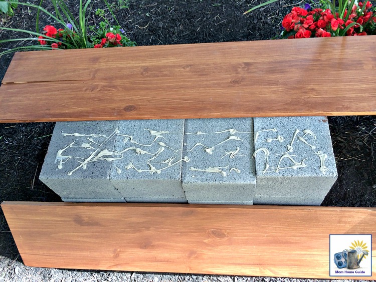 Use landscape adhesive to glue wood boards to the top of a stack of cinder blocks to create a study and inexpensive bench!