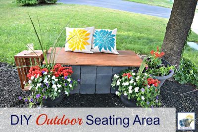 DIY outdoor seating area with a DIY cinder block and wood bench and stenciled pillows