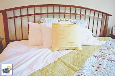 Beautiful curved head board in a master bedroom with blue and gray quilt