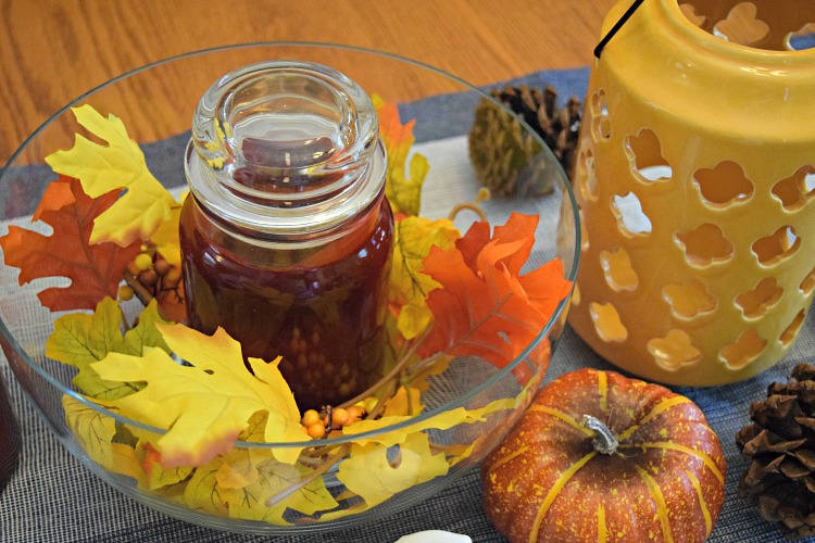 Fall kitchen table centerpiece with candles, faux leaves and cinnamon scented pine cones