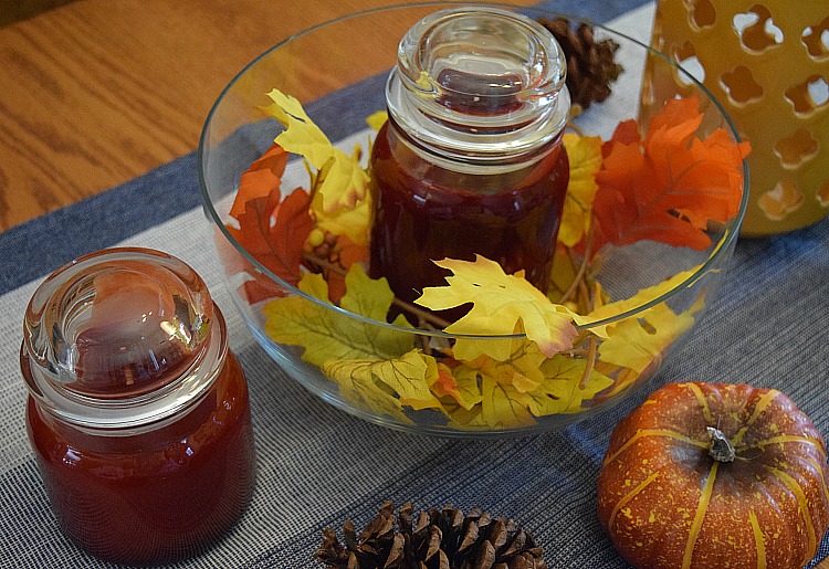 Fall kitchen candle centerpiece with candles, faux fall leaves and cinnamon scented pine cones