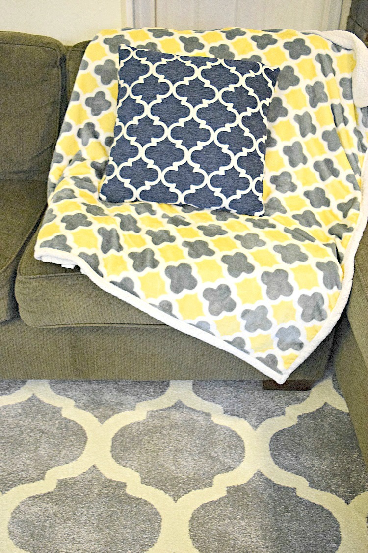 Living room with gray geometric rug, green sofa and geometric-print pillow and throw