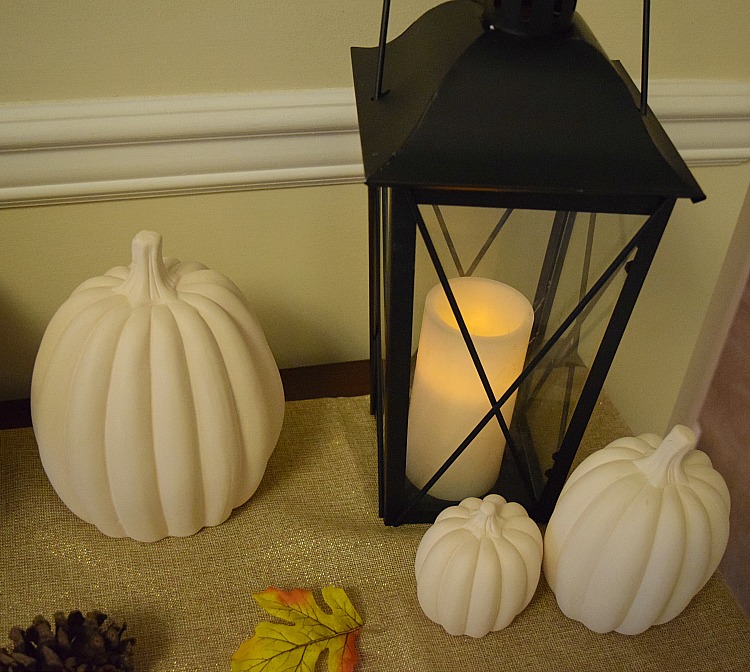 White pumpkins with a black metal lantern with a flickering flameless wax candle