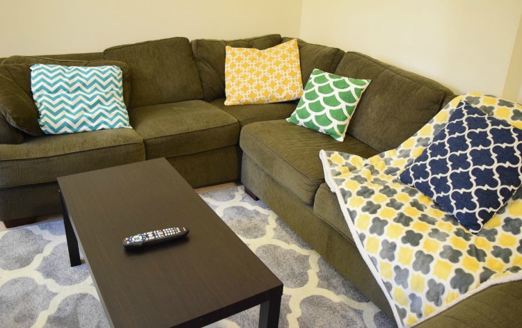Family room with geometric gray rug and sectional sofa with colorful throw pillows