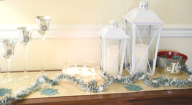 Christmas console table with white lanterns, frosted pine, tall glass votive candles and floating candles