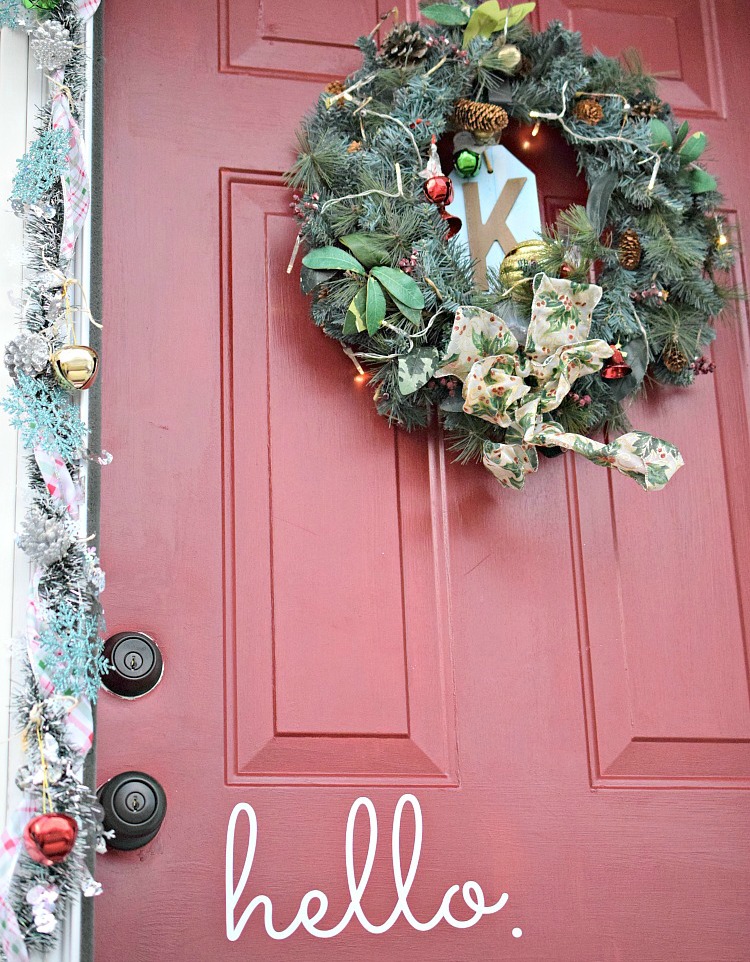 a festive red front door decorated wiith a garland and a wreath for Christmas using Command Brand products