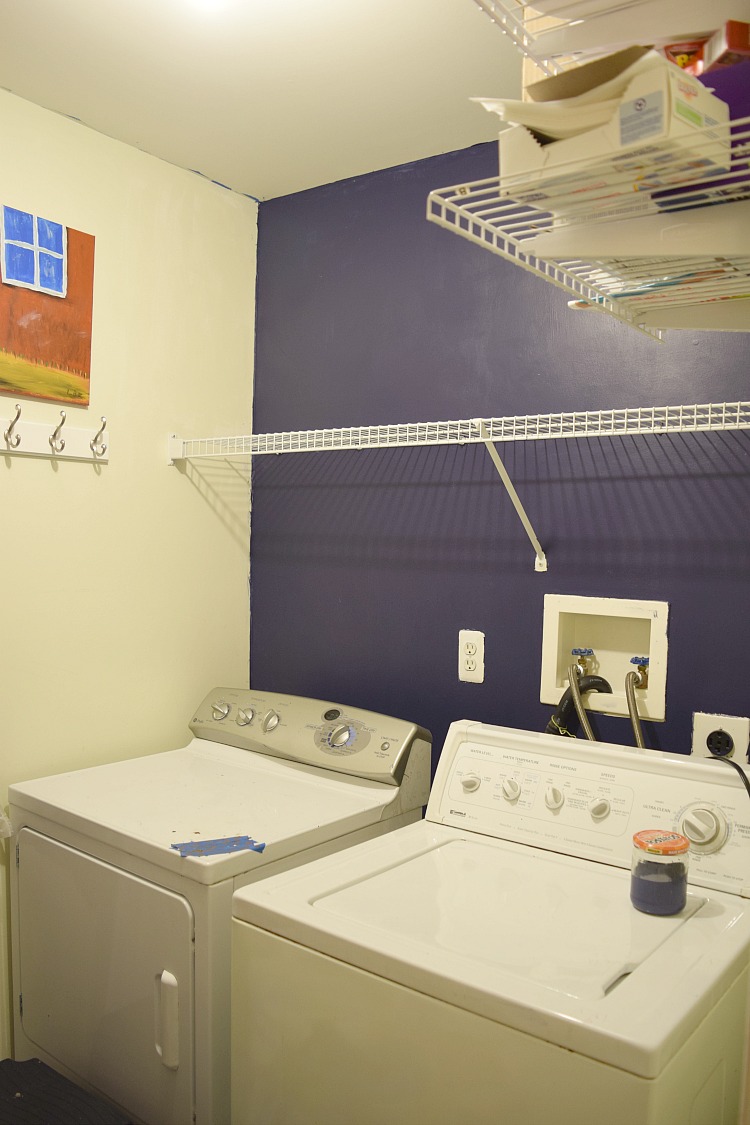Laundry room with a white washer and dryer and a navy blue feature wall