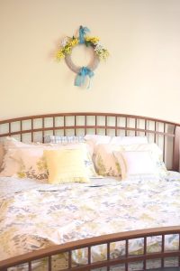 farmhouse style bedroom with arched slatted bed and forsythia gray and yellow bedding