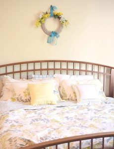 farmhouse style bedroom with arched slatted bed and forsythia gray and yellow bedding
