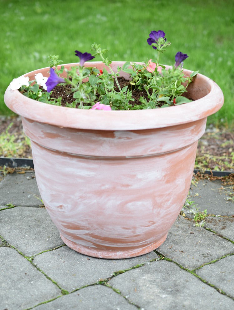 diy white washed plastic flower pot on a gray paver patio
