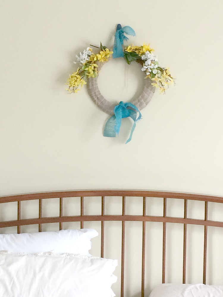 Faux forsythia floral dollar store wreath over bed in master bedroom