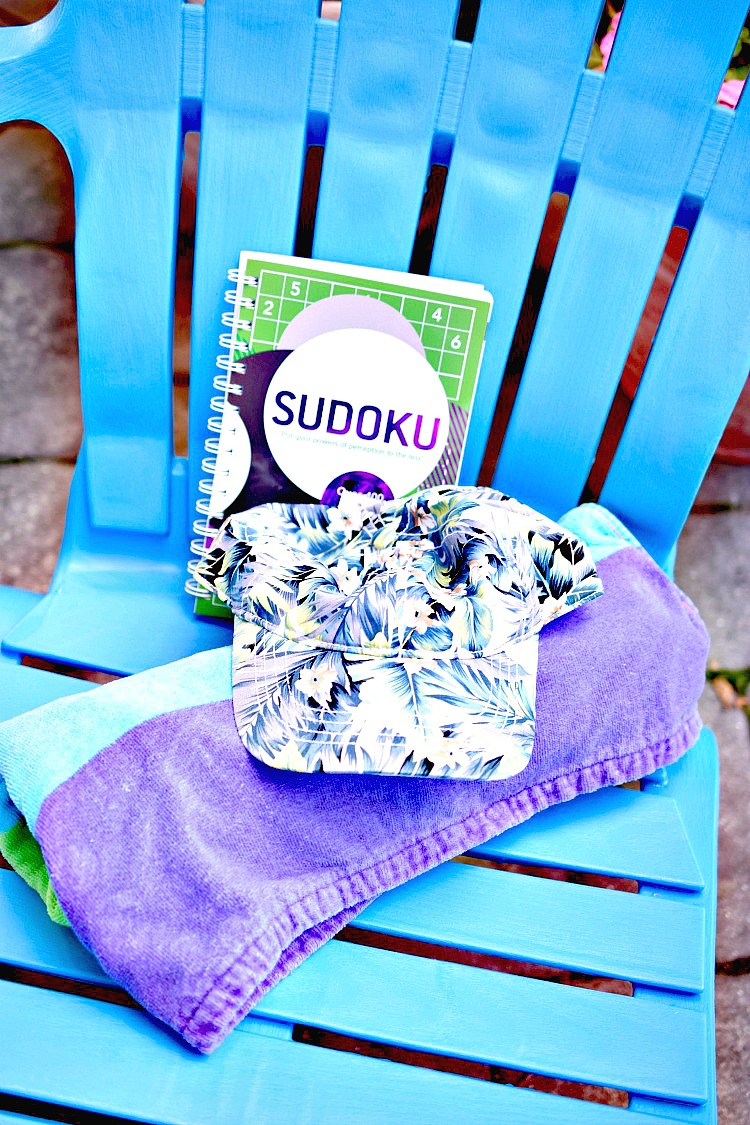 A colorful Adirondack chair with a beach towel, summer hat and Sudoku are great summer gifts