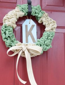 white and green burlap bubble wreath on a red front door