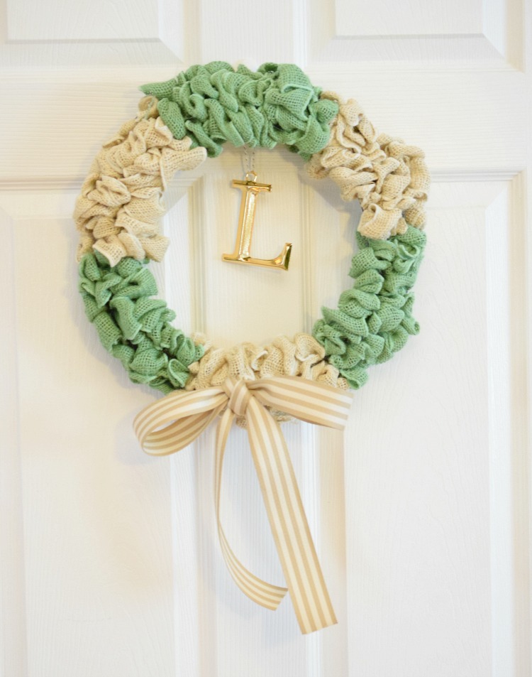 DIY white and green burlap bubble wreath against a front door with a gold monogram letter