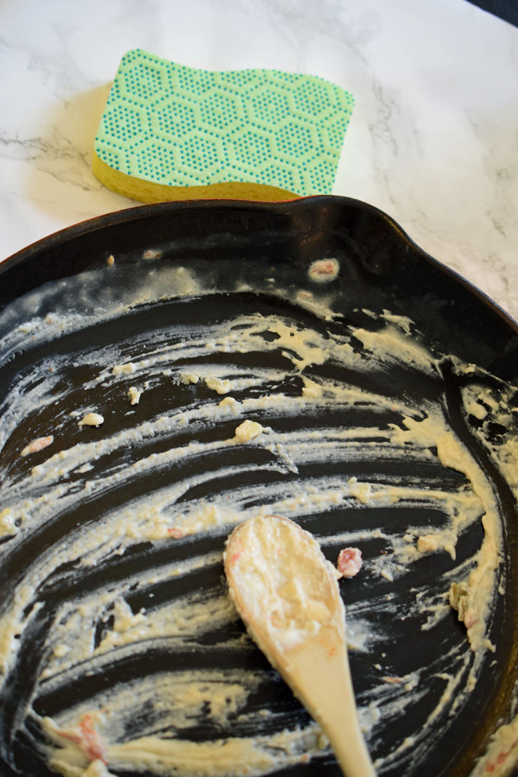 Cleaning a baked-on cheesy cast iron pan with a Scotch-Brite Scrub dots sponge