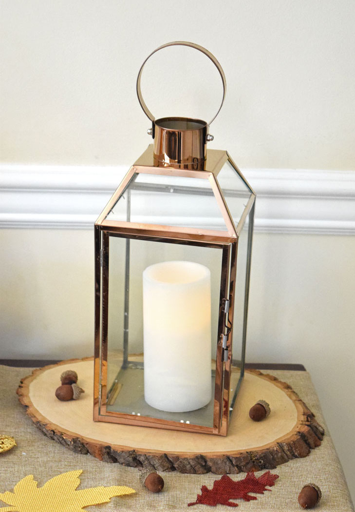 fall lantern on a natural wood slice on a console table