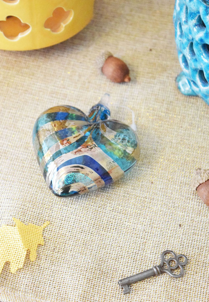 glass heart ornament, antique key, burlap leaves and craft acorns on a console table