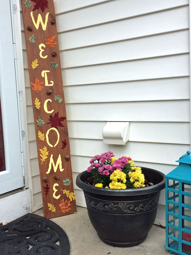 Fall porch with DIY welcome sign, blue lantern and potted mums