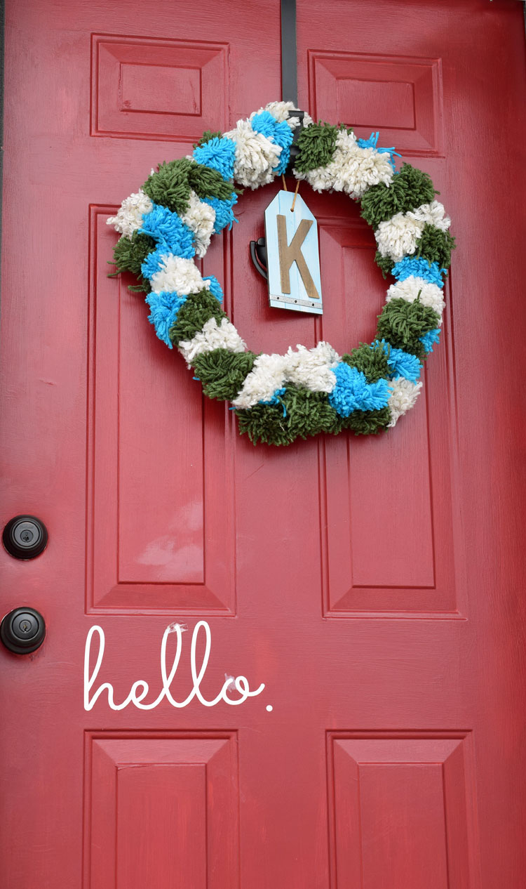 festive Christmas holiday pom pom wreath on a red front door