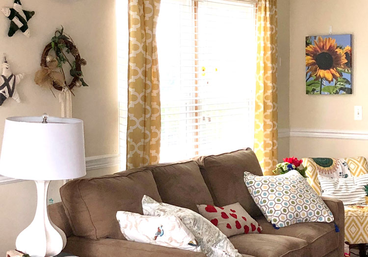 Living room with brown sofa, colorful pillows, yellow curtains and a DIY gallery wall