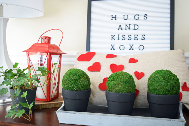 Valentne's Day console table with burlap heart pillow, red lanterns, letter board, gray trayb potted moss and English ivy