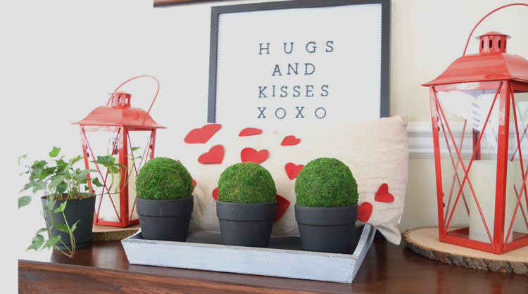 Valentne's Day console table with burlap heart pillow, red lanterns, letter board, gray trayb potted moss and English ivy