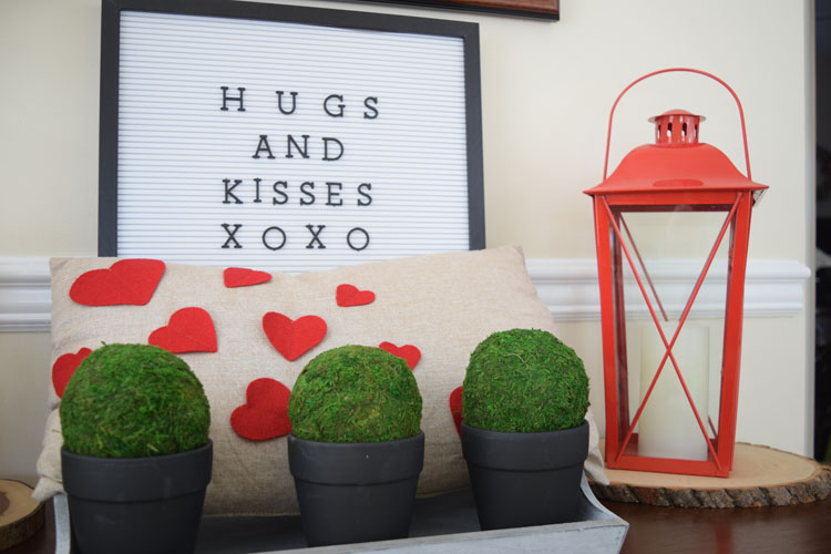 Valentne's Day console table with burlap heart pillow, red lanterns, letter board, gray trayb potted moss and English ivy