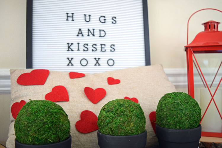 Valentne's Day console table with burlap heart pillow, red lanterns, letter board, gray trayb potted moss and English ivy