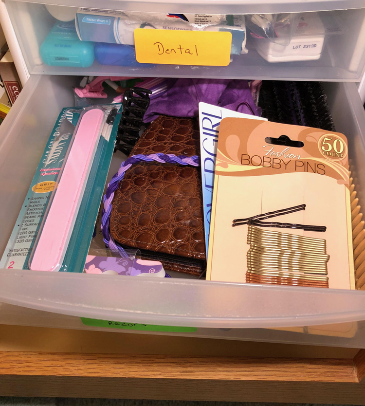 A plastic drawer used to store hair supplies, razors and nail supplies in a bathroom