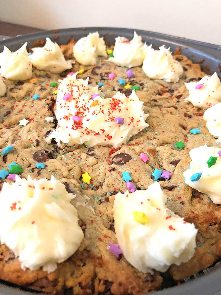 A homemade chocolate chip cookie cake made from a recipe and decorated with colorful sprinkles