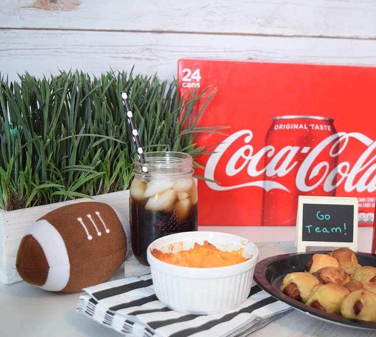 box of 24 cans of Coca-Cola at a fun football watch party with mini pretzel dogs and pimento cheese dip