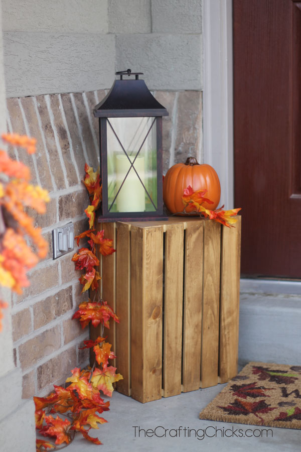 small front porch with a crate, pumpkin and black lantern