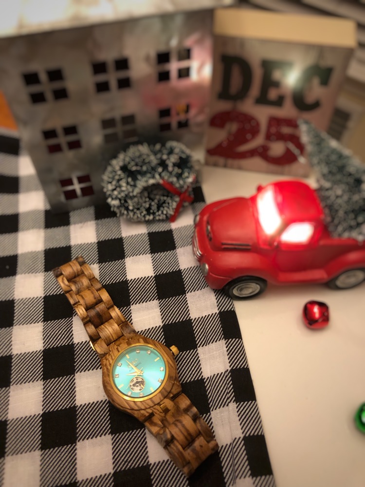 A Jord wood watch with a mini red Christmas pickup truck and Christmas tree, galvanized metal house and buffalo plaid napkin