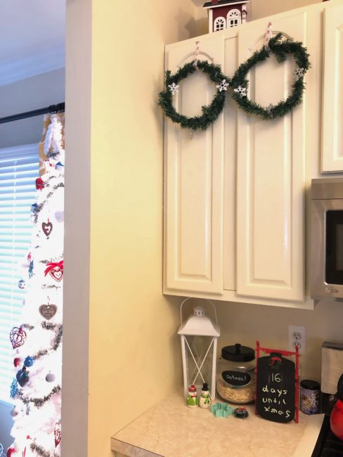 Mini wreaths from the dollar store on kitchen cabinet doors for Christmas. Plus, you won't believe the super easy way to hang these up!