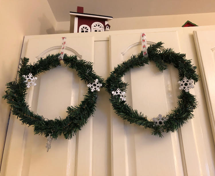 Dollar store wreaths hung on white kitchen cabinets