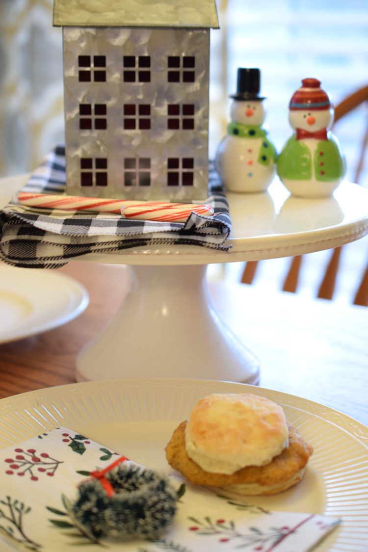 Cute raised holiday display on a Christmas table with Christmas napkins, place setting and breakfast sandwich