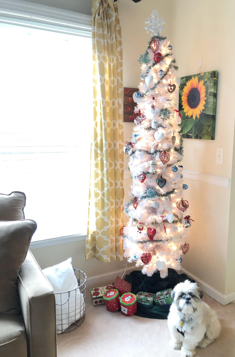 A white Christmas tree with colorful ornaments and a white Shih Tzu puppy