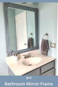 DIY blue bathroom mirror frame made from molding and corner rosettes