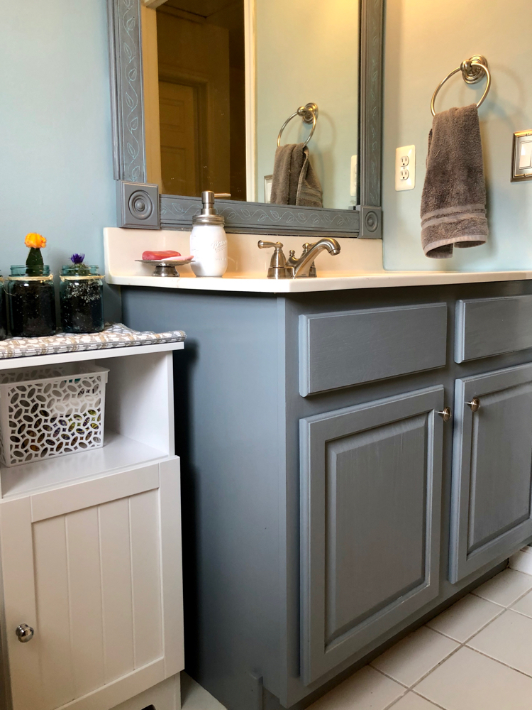 A blue bathroom with a gray painted bathroom cabinet, DIY bathroom mirror and mason jar succulents..