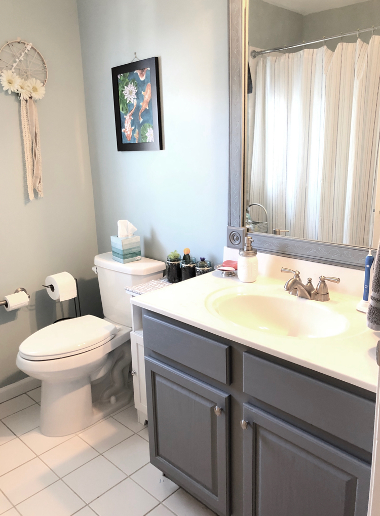 Updated bathroom with DIY wall art, painted vanity and DIY mirror frame and Yarsmouth Blue Benjamin Moore paint.