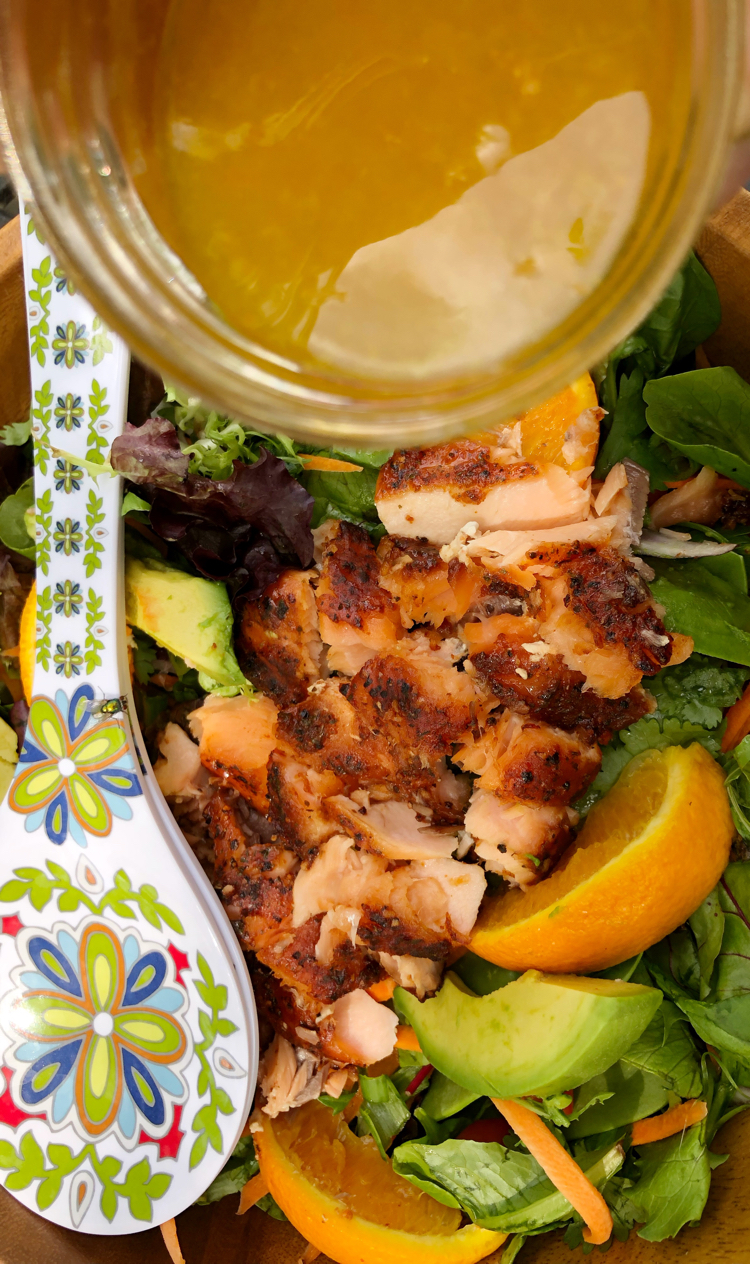 A fresh green salad with grilled orange ginger salmon, oranges, avocado and a homemade salad dressing.