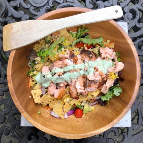 Green salad with salmon and avocado and a creamy cilantro dressing. Plus, it's topped with crushed tortilla chips.