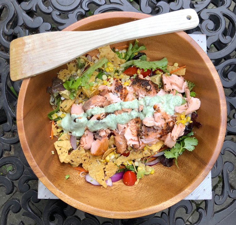 Green salad with salmon and avocado and a creamy cilantro dressing. Plus, it's topped with crushed tortilla chips.