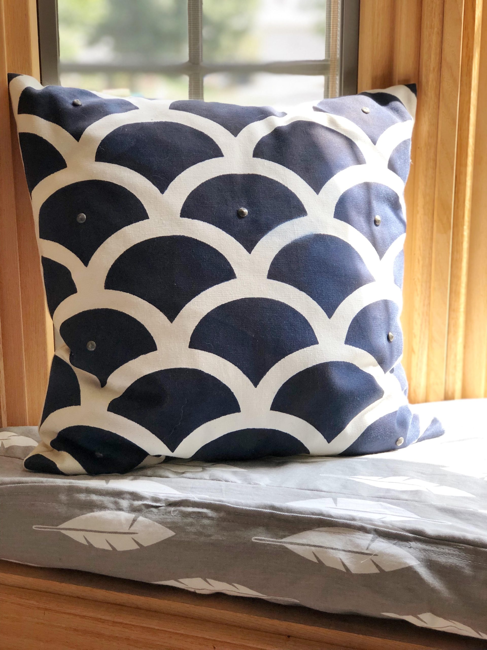 A DIY box cushion with homemade piping. Also shown is a DIY stenciled pillow