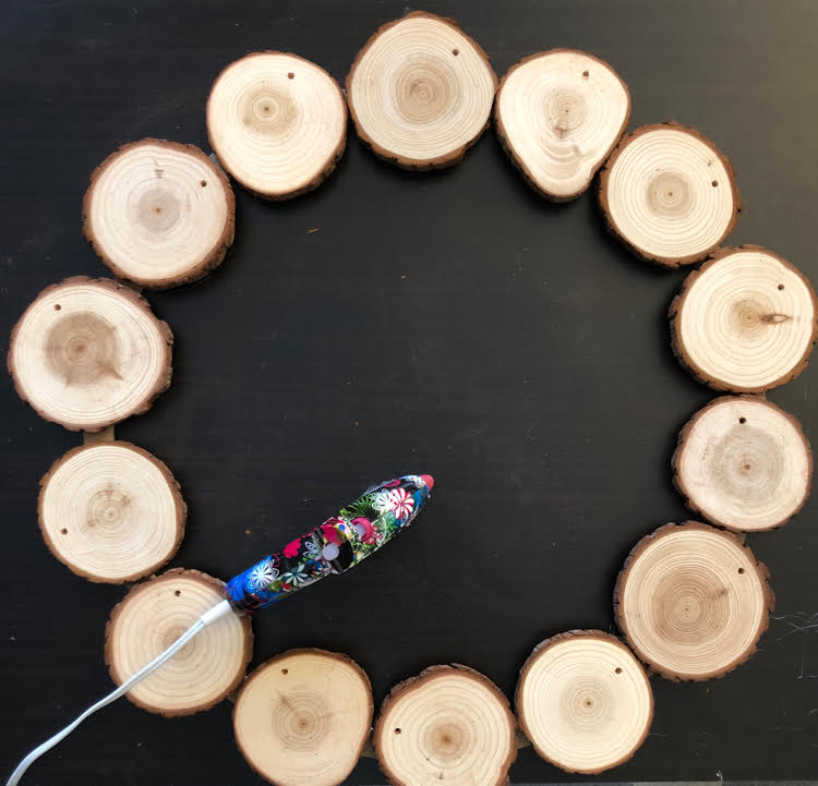 Gluing wood slices on a large embroidery hoop to make a wreath for the holidays