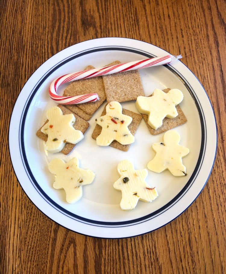 A festive platter of cheese and crackers for the holidays. The cheese is cut with mini cookie cutters