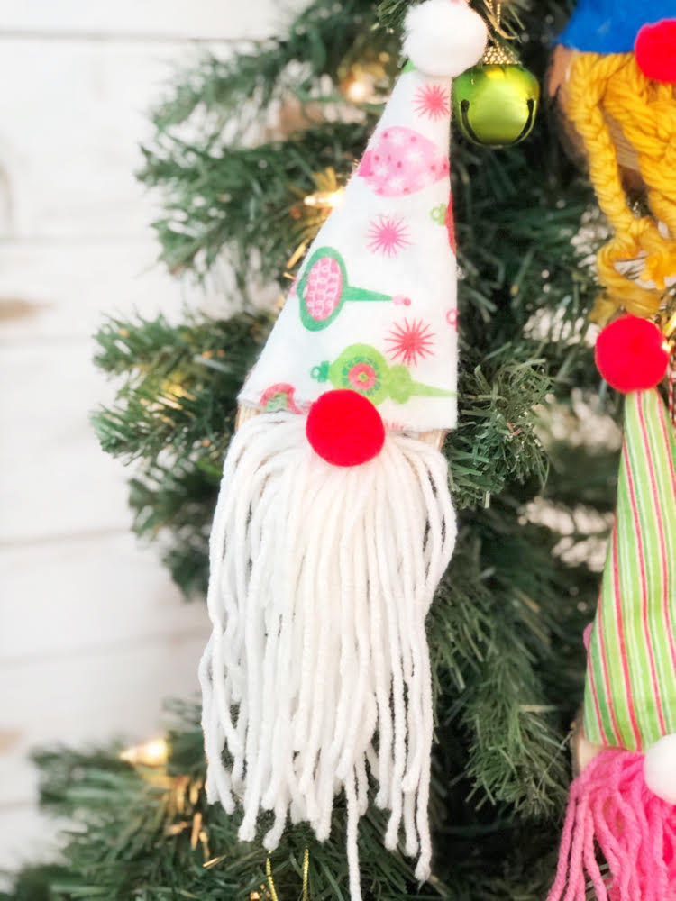 A cute DIY gnome ornament made with a wood slice, felt, yarn and two pom poms.